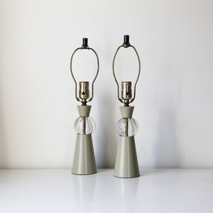 May include: A pair of mid-century modern table lamps with a beige ceramic base and a clear glass globe shade.