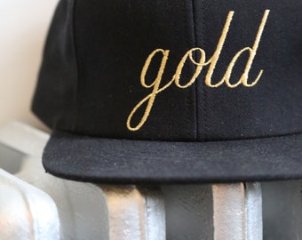 Snap back black baseball cap with gold embroidered logo