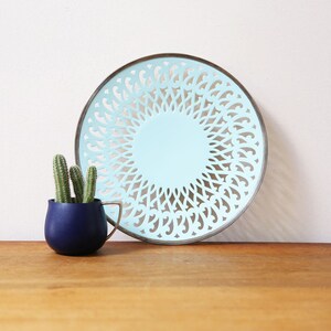 May include: A light blue decorative plate with a silver rim and a cut-out design. The plate is round and has a delicate, intricate pattern.