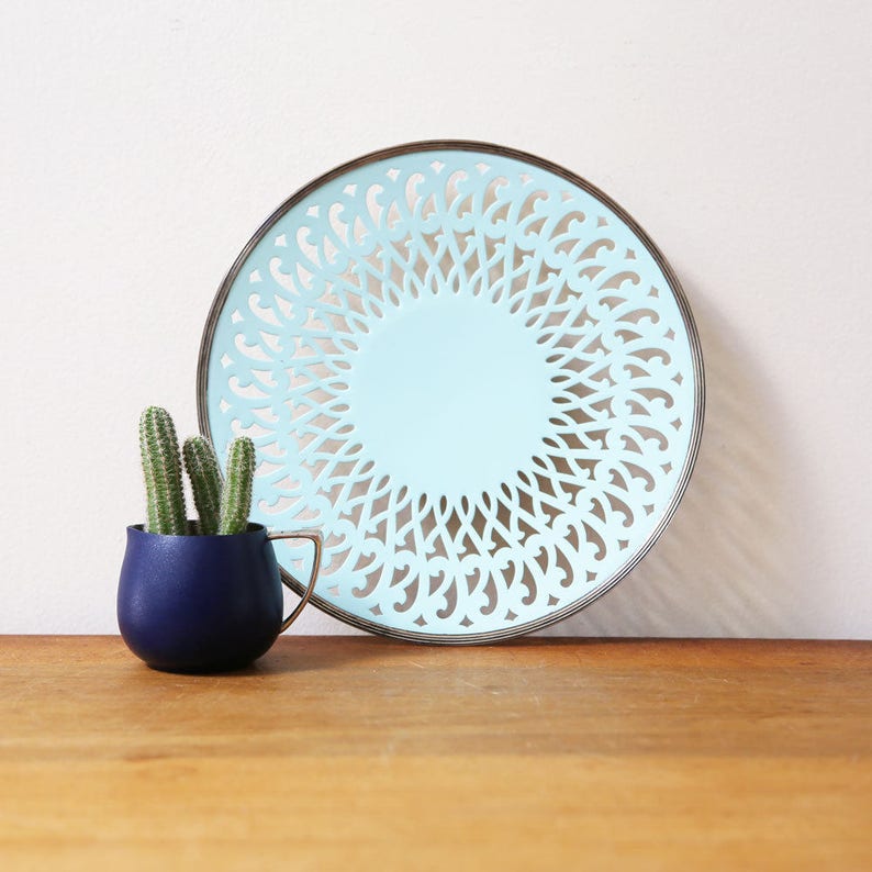 May include: A light blue decorative plate with a silver rim and a cut-out design. The plate is round and has a delicate, intricate pattern.