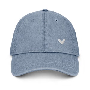 May include: A blue denim baseball cap with a white heart embroidered on the front.
