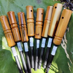 Peut inclure: Huit allume-feux en bois avec des tiges métalliques noires. Les allume-feux sont numérotés de 1 à 8. Les allume-feux sont sur un coussin de cactus vert.