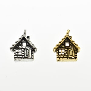 May include: Two small house-shaped charms, one silver and one gold. Both charms have a brick pattern and a small window and door.
