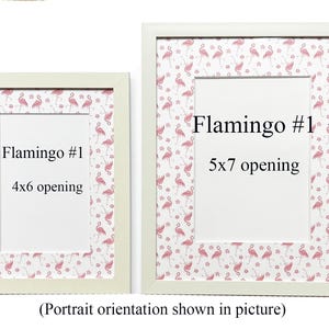 May include: Two white picture frames with flamingo-patterned borders. The frames have openings for 10x15 cm and 13x18 cm photos, with the text "Flamingo #1" on each. The image is in portrait orientation.