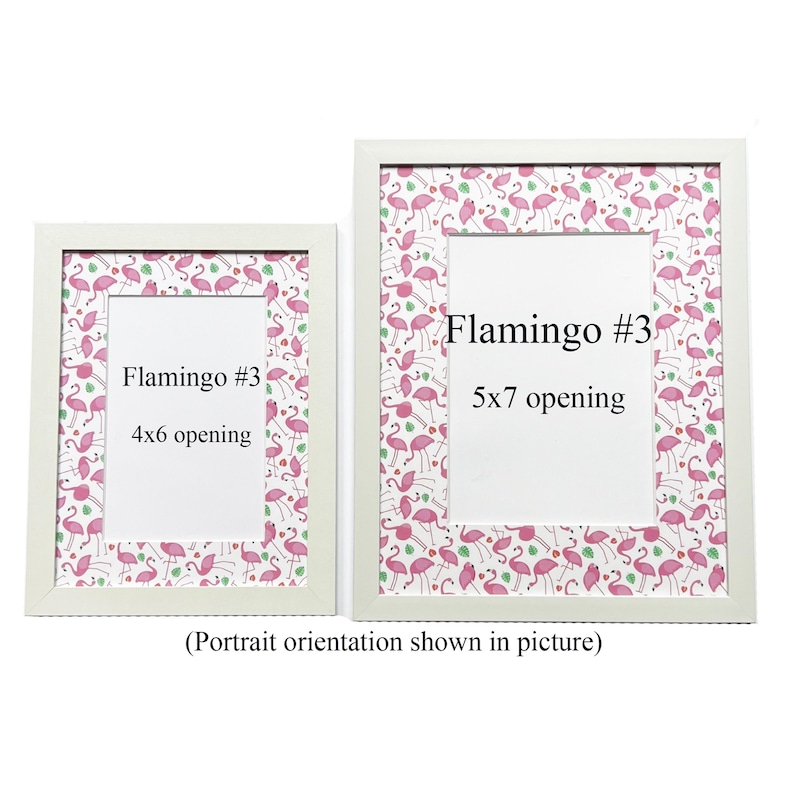 May include: Two white picture frames with a flamingo pattern border and white openings. The frames are labelled "Flamingo #3" with 10x15 cm and 13x18 cm openings. The text "(Portrait orientation shown in picture)" is below the frames.