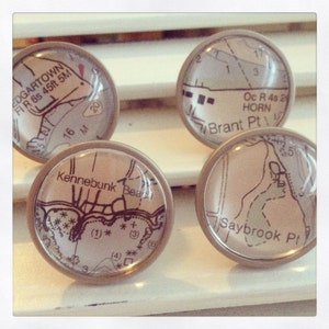 May include: Four round, glass, map-themed drawer knobs with silver metal bases. The maps show locations like Edgartown, Kennebunk Beach, Brant Point, and Saybrook Point.