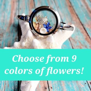 May include: A silver charm bracelet with a round glass locket containing a small sea turtle, seashells, and a blue flower.  Choose from 9 colors of flowers!