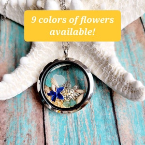 May include: A silver locket necklace with a glass insert filled with seashells, sand, and a blue flower. The locket is hanging from a white starfish on a blue and white wooden background. The text "9 colors of flowers available!" is displayed on a yellow banner.