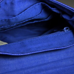 Pode incluir: Vista aberta de uma bolsa transversal azul cobalto. O interior apresenta um bolso com z&iacute;per e forro de tecido. O exterior da bolsa tem uma apar&ecirc;ncia texturizada. A al&ccedil;a de corrente &eacute; vis&iacute;vel no lado direito.