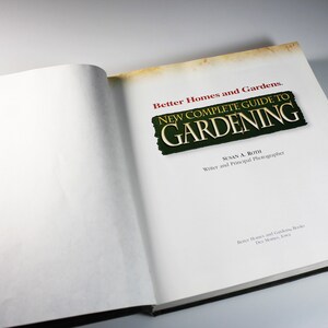 May include: A closed book titled "Better Homes and Gardens. New Complete Guide to Gardening" with a green and gold title on a white background.