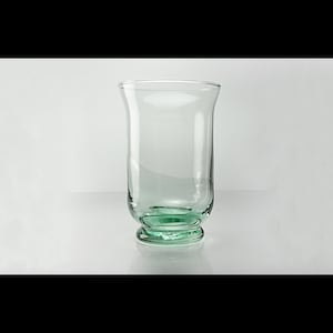 May include: A clear glass tumbler with a green base. The glass has a wide mouth and a rounded bottom.