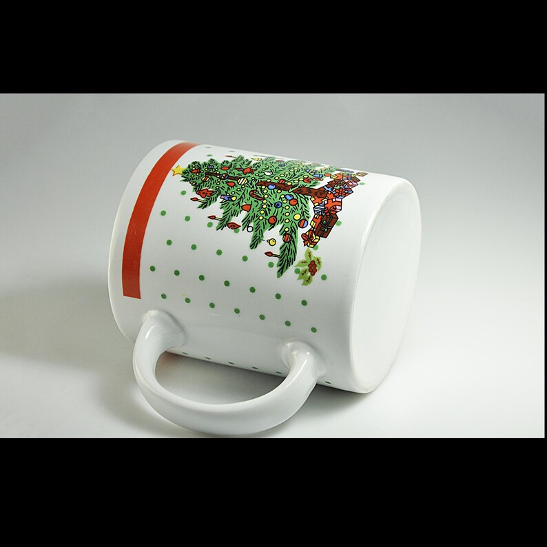 May include: White ceramic mug with a red and white polka dot pattern and a Christmas tree design. The tree is decorated with baubles and presents.
