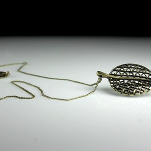 May include: A gold chain necklace with a delicate, intricate leaf pendant. The leaf is made of metal and has a detailed, openwork design.