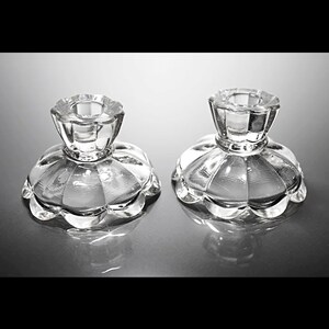 Puede incluir: Dos candelabros de vidrio transparente con base festoneada y parte superior acanalada.
