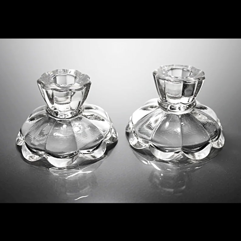Puede incluir: Dos candelabros de vidrio transparente con base festoneada y parte superior acanalada.