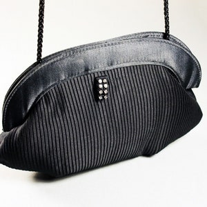 May include: A black satin evening bag with a pleated design and a rhinestone clasp.