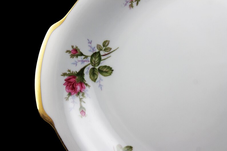 Puede incluir: Plato de servir ovalado blanco con borde dorado y un dise&ntilde;o floral con rosas rosas y hojas verdes.