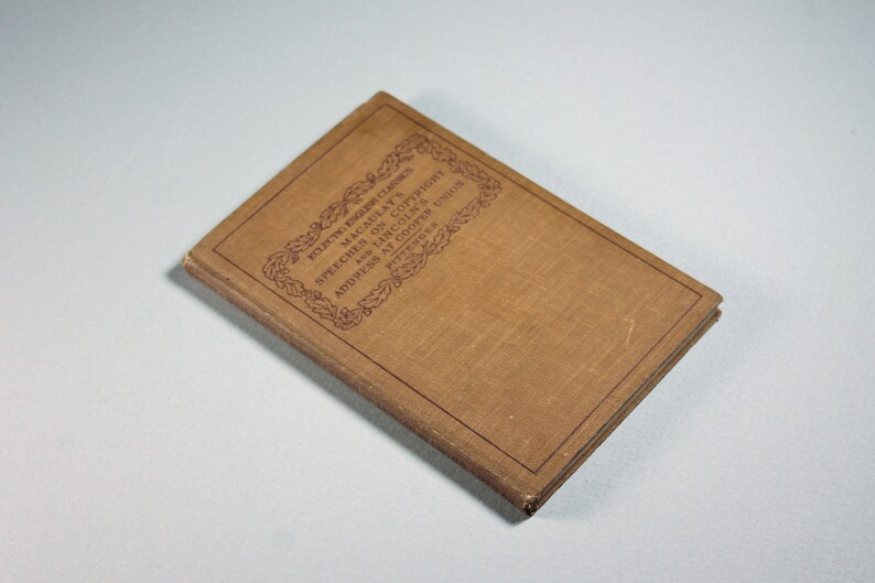 Op de afbeelding: Een bruin boek met een rode titel op de kaft. De titel luidt "Selected Poems of Thomas Babington Macaulay" en "Speeches on Copyright and  Address at Cooper's Union,  1859".