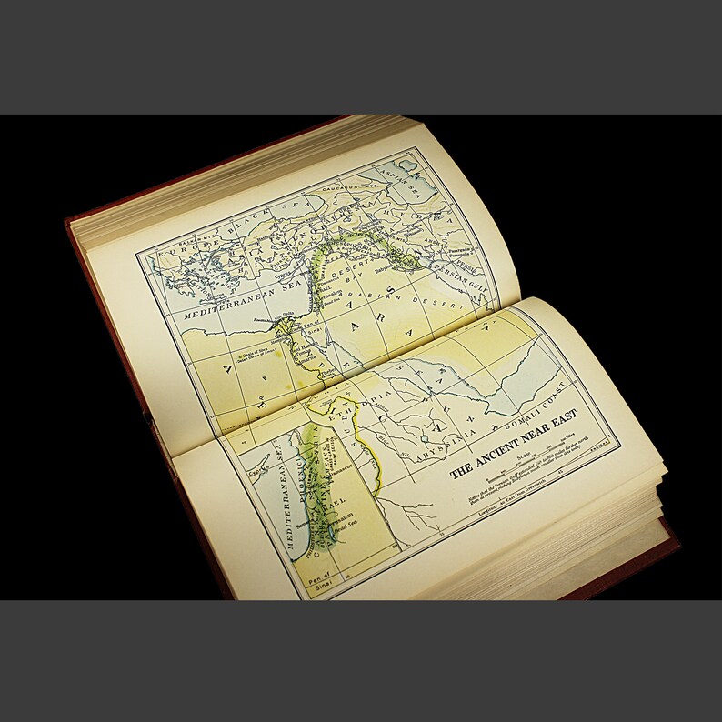 May include: An open book with a map of the Ancient Near East. The map shows the Mediterranean Sea, the Persian Gulf, and the Arabian Desert. The text "The Ancient Near East" is printed at the bottom of the page.