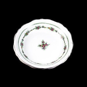 May include: White ceramic bowl with a scalloped edge and a floral design in shades of green, pink, and purple. The bowl has a delicate floral pattern around the rim and a larger floral design in the center.