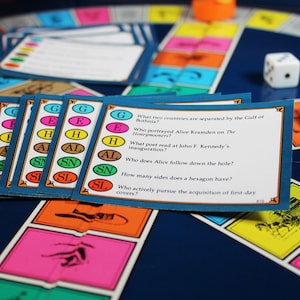 以下が含まれることがあります： 青いゲームボードにカラフルなマスと、トリビア問題が書かれた青いカードの山があります。カードには、文字が書かれた異なる色の円があります。カードのテキストは、「ボトニア湾で隔てられている2つの国は？」、「The Honeymoonersでアリス・クラムデンを演じたのは誰？」、「ジョン・F・ケネディの就任式で詩を読んだのは誰？」、「アリスは穴に誰を追いかけていくのですか？」、「六角形はいくつ辺がありますか？」、「初日カバーの取得を積極的に追求するのは誰ですか？」です。