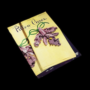May include: A vintage book cover for "Pillow Cases" featuring a crocheted orchid flower in shades of purple and green. The book cover is yellow with the title "Pillow Cases" in a decorative font. The text "Decorative Crochet" is printed below the title. The book is titled "Book No. 344" and the price is 10 cents.