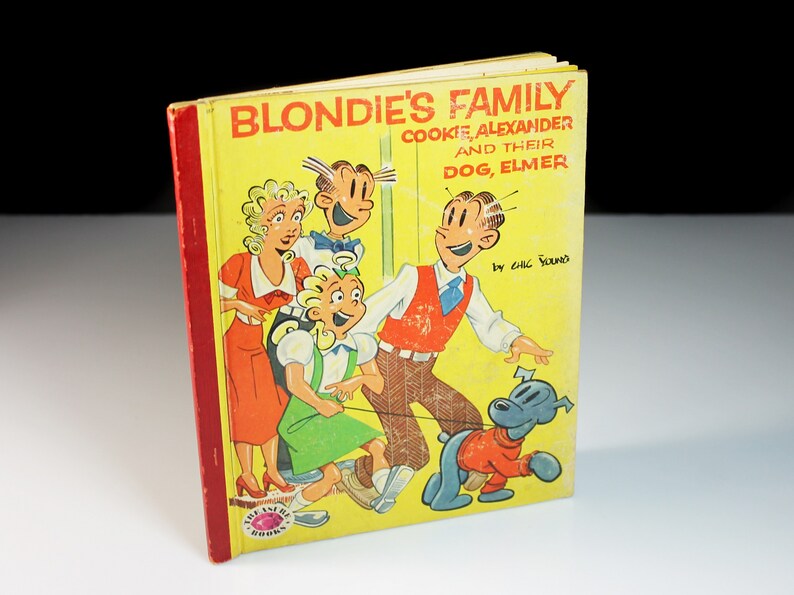 May include: A vintage book cover featuring a cartoon family, Blondie's Family, with the title "Blondie's Family, Cookie, Alexander and their Dog, Elmer" by Chic Young. The cover is yellow with red and blue accents.
