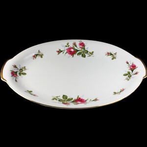 Puede incluir: Plato de servir ovalado blanco con borde dorado y dise&ntilde;o floral con rosas rosas y hojas verdes.