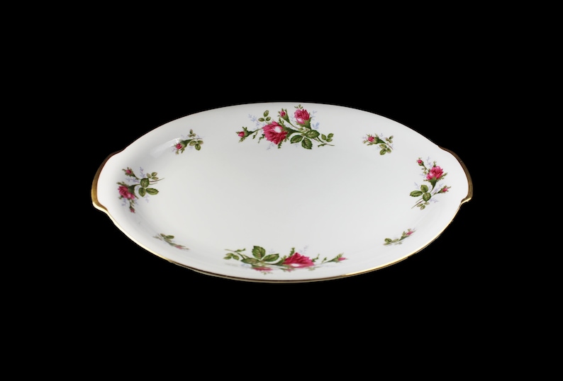 Puede incluir: Plato de servir ovalado blanco con borde dorado y dise&ntilde;o floral con rosas rosas y hojas verdes.