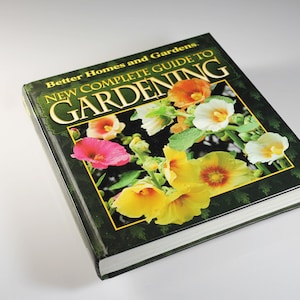May include: A green book titled "New Complete Guide to Gardening" by Better Homes and Gardens. The cover features a close-up of colorful flowers.