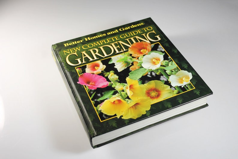 May include: A green book titled "New Complete Guide to Gardening" by Better Homes and Gardens. The cover features a close-up of colorful flowers.