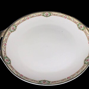 May include: A white oval serving dish with gold trim and a floral design. The dish has two handles on the sides.