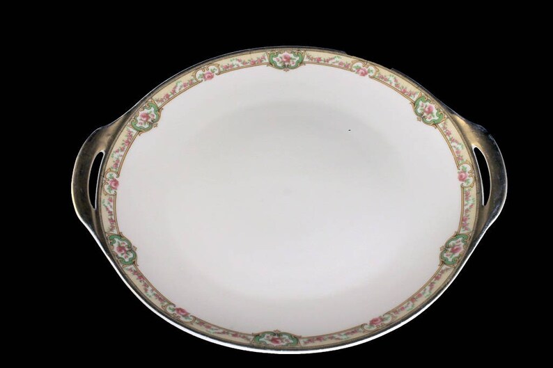May include: A white oval serving dish with gold trim and a floral design. The dish has two handles on the sides.