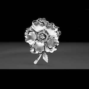 Könnte beinhalten: Eine silberne Brosche in Form einer Blume mit einem detaillierten Design. Die Blume hat fünf Blütenblätter und eine Mitte mit einem Wirbelmuster. Die Brosche hat einen Stiel und ein Blatt.