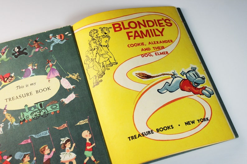 May include: A green and yellow book with the title "This is my TREASURE BOOK" on the front cover. The back cover features a cartoon illustration of Blondie's family, including Cookie, Alexander, and their dog, Elmer. The text on the back cover reads "BLONDIE'S FAMILY COOKIE, ALEXANDER AND THEIR DOG, ELMER TREASURE BOOKS NEW YORK."
