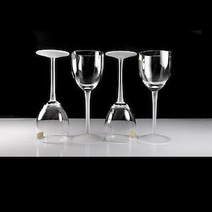 Puede incluir: Cuatro copas de vino de vidrio transparente con borde esmerilado. Las copas están dispuestas en fila sobre una superficie blanca.