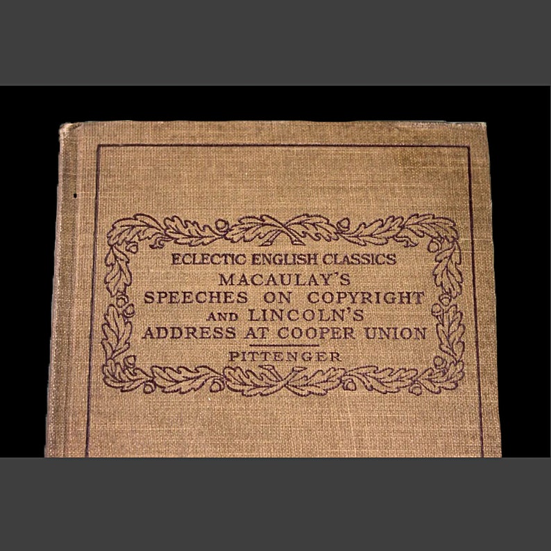 Op de afbeelding: Een bruin boek met een bordeauxrode rand en tekst die luidt "Eclectic English Classics Macaulay's Speeches on Copyright and Lincoln's Address at Cooper Union Pittenger".