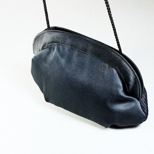 May include: A black satin clutch bag with a chain strap.