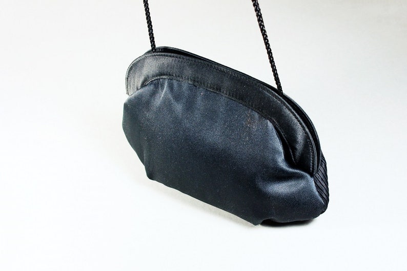 May include: A black satin clutch bag with a chain strap.