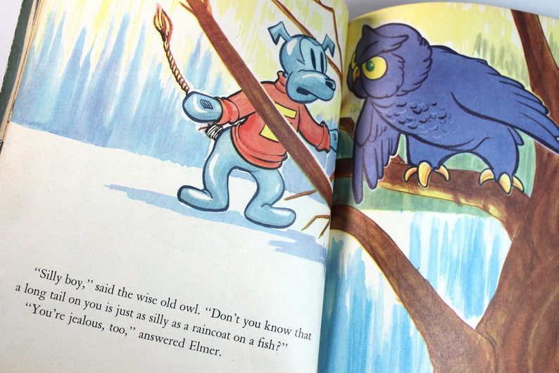 May include: An illustration of a blue dog with a red sweater and a long tail, and a purple owl perched on a branch. The dog is holding a rope with a lit match on the end. The text reads, "Silly boy," said the wise old owl. "Don't you know that a long tail on you is just as silly as a raincoat on a fish?" "You're jealous, too," answered Elmer.