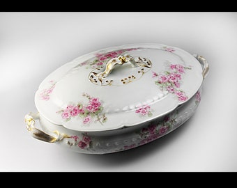 May include: White oval porcelain serving dish with a lid. The dish is decorated with pink and green floral designs and gold accents. The lid has a gold handle.