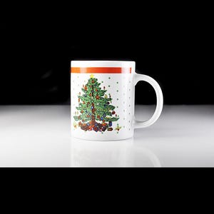 May include: White ceramic mug with a red and white stripe around the top. The mug features a green Christmas tree with colourful ornaments and presents at the base.