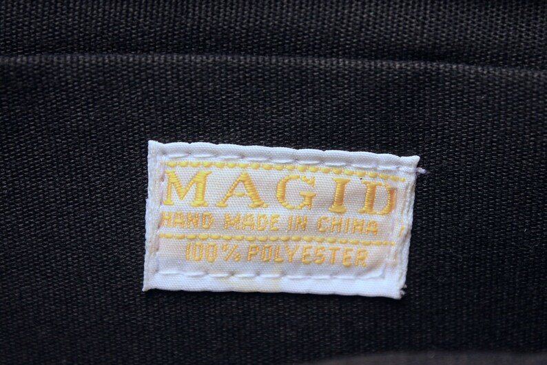 May include: White label with gold stitching and the text "MAGID HAND MADE IN CHINA 100% POLYESTER"