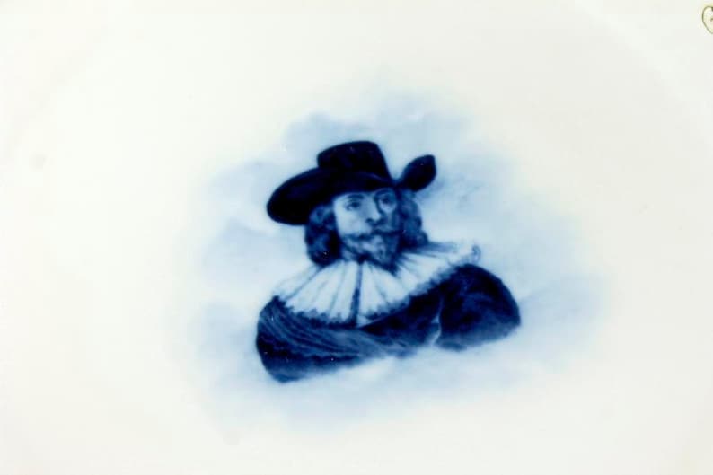 May include: A blue and white porcelain plate with a portrait of a man in a hat and a ruff collar.