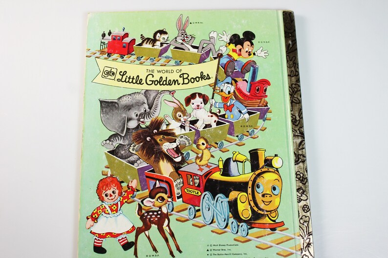 K&ouml;nnte beinhalten: Ein Vintage-Cover eines Little Golden Books mit einem bunten Zug mit verschiedenen Figuren, darunter Mickey Mouse, Donald Duck, ein L&ouml;we, ein Elefant, ein Reh, ein Kaninchen und eine Puppe. Der Titel des Buches lautet "The World of Little Golden Books".