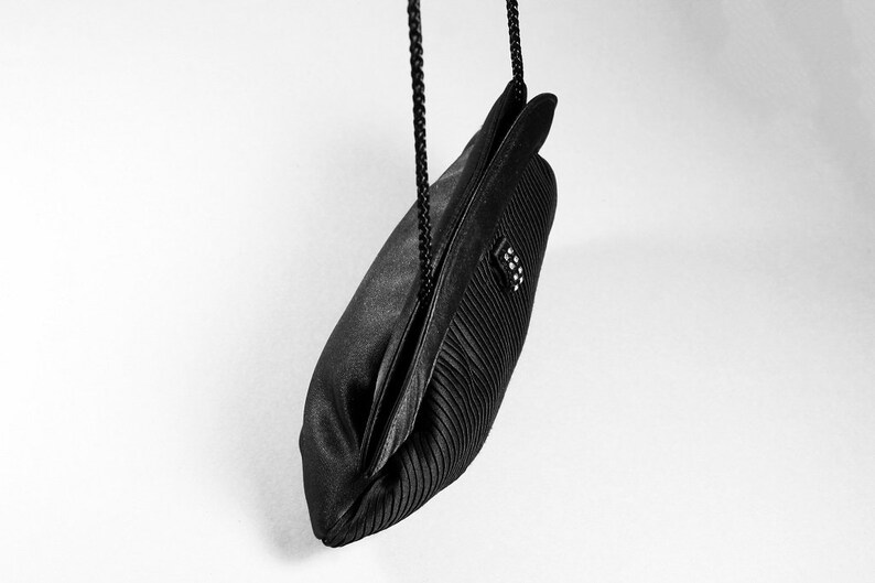 May include: A black satin evening bag with a pleated design and a black chain strap.