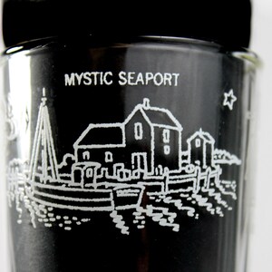 以下が含まれることがあります： 側面に「MYSTIC SEAPORT」の文字が書かれた、小さな町が白く描かれた黒いガラス