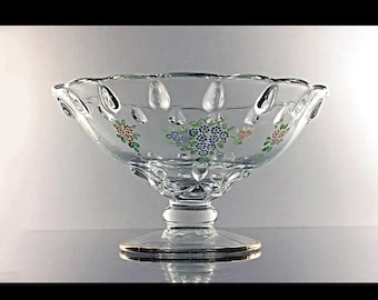 May include: A clear glass pedestal bowl with a scalloped rim and a floral design. The bowl has a delicate, hand-painted design of small flowers in shades of blue, green, orange, and red.