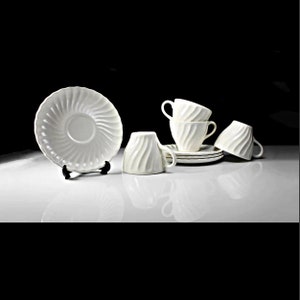 May include: A set of six white ceramic teacups and saucers with a swirling design. The cups and saucers are arranged on a white surface.