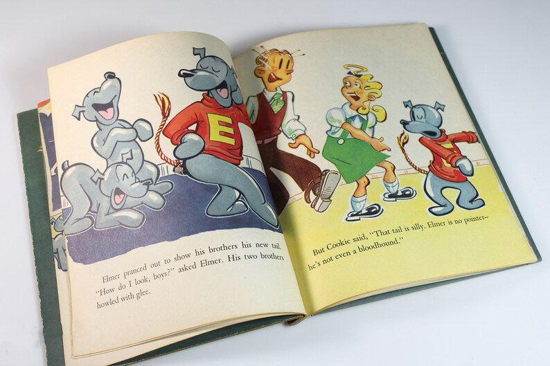 May include: An open book with a cartoon illustration of a dog with a long tail. The dog is wearing a red sweater with a white letter E on it. The text in the book reads "How do I look, boys?" and "That tail is silly. Elmer is no pointer - he's not even a bloodhound."